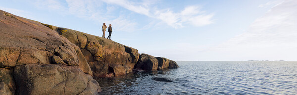 Two people on a rock by the calm sea